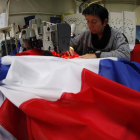 Una trabajadora de la empresa Doublet cose una bandera francesa, ayer en Lille.-AP / MICHEL SPLINGER