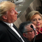 Clinton, sentada junto al obispo de Nueva York, observa a Trump durante su intervención en la cena benéfica del jueves.-REUTERS / CARLOS BARRIA