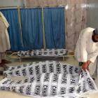 Un hombre cubre los cuerpos de las víctimas del atentado bomba-/ JAMAL TARAQAI / EFE
