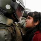 Una manifestante mira a un policía durante una marcha con motivo del 43 aniversario del golpe de Estado en Chile.-CARLOS VERA / REUTERS