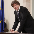 El president Carles Puigdemont en el momento de firmar la declaración, tras el pleno.-JULIO CARBÓ
