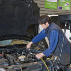 Un trabajador extrae el aceite de un vehículo en un taller mecánico.-SIGAUS