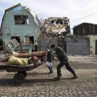 Un hombre empuja una carretilla ante una vivienda destruida por los combates en la ciudad de Debáltsevo , Ucrania.-Foto: REUTERS / BAZ RATNER