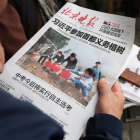 Un hombre lee un periódico donde aparece en portada el presidente Xi en una plantación de árboles, el 6 de abril, en Pekín.-AFP