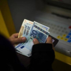 Una mujer saca dinero de un cajero automático. ECB