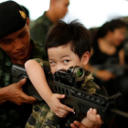 Un soldado tailandés muestra a un niño cómo funciona un arma en la celebración del Día del Niño.-REUTERS / JORGE SILVA
