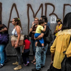 Venezolanos hacen cola frente a una pintada con la palabra hambre, en Caracas.-JUAN BARRETO (AFP)