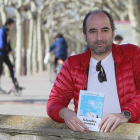 Ismael Ali de Unzaga posa en el paseo del Espolón con uno de los ejemplares de ‘Islandia, noniná’, su primera novela.-Raúl Ochoa