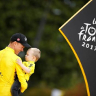 Chris Froome, el ciclista británico, sostiene en brazos a Kellan, su hijo, en el podio de París.-REUTERS / CHRISTIAN HARTMANN