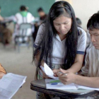 Dos alumnos atienden a las explicaciones de una profesora en Nopoki.-ONGD PERSONA SOLIDARIDAD