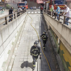 Dos bomberos acceden a la entrada del garaje ante la mirada de los vecinos.-SANTI OTERO