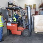 Un voluntario del banco de Alimentos descarga una caja con productos de un camión.-RAÚL G. OCHOA