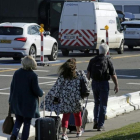 Varias personas caminan hacia la terminal mientras los vehículos hacen cola en un control de seguridad, en el aeropuerto de Zaventem, este lunes.-AFP / THIERRY ROGE