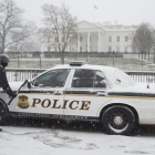 Un miembro del servicio secreto limpia la nieve de un vehículo en la Avenida Pennyslvania.-EFE/ JIM LO SCALZO