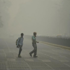 Peatones en medio de una intensa niebla toxica en Nueva Delhi.-AFP / SAJJAD HUSSAIN