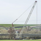 Una grúa de grandes dimensiones ha empezado a descolgar vías, barandillas y otros elementos del puente.-ISRAEL L. MURILLO