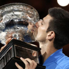 Novak Djokovic besa el trofeo que le acredita como campón del Abierto de Australia.-AP