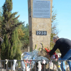 Varias personas depositan flores en el monumento del monte de La Pedraja.-ICAL