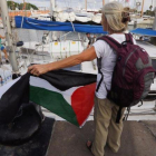 Una activista con la bandera palestina frente a uno de los dos veleros de la flotilla que ha partido hacia Gaza.-JULIO CARBÓ