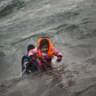 Un hombre ayuda a un niño cuyo barco ha naufragado este domingo en el Egeo.-AFP