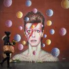 Flores ante un mural de David Bowie en la pared del comercio Morley, en Brixton (Londres), lugar de nacimiento del cantante.-