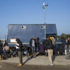 Inmigrantes del campamento francés de Calais usan teléfonos móviles junto a un camión que ofrece conectividad.-JACK TAYLOR