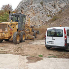 Una máquina motoniveladora junto a una furgoneta de la institución provincial durante la reparación de un camino.-ECB