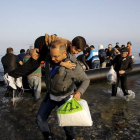 Un refugiado sirio llegado de Turquía carga con un niño en la isla griega de Kos.-Foto: REUTERS / YANNIS BEHRAKIS