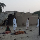 Algunos fieles deambulan junto a los cuerpos de las víctimas del atentado en Pakistán, este jueves-AFP