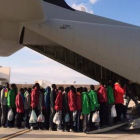 Inmigrantes subsaharianos hacen cola antes de subir a un avión militar que les trasladará a la península italiana, este lunes, en Lampedusa.-