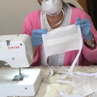 Una mujer confecciona una mascarilla con máquina de coser. ECB