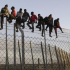 Policías españoles tratan de disuadir a inmigrantes encaramados a la valla de Melilla, fronteriza con Marruecos, el 22 de octubre del 2014.-EFE / FRANCISCO G. GUERRERO