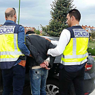Dos agentes introducen a uno de los detenidos en un coche.-ECB