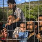 Refugiados e inmigrantes esperan tras una verja, en un campo de fútbol, a poder ser registrados, en Mitilene, este martes.-AP / SANTI PALACIOS