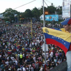 Un simpatizante de la oposición ondea una bandera venezolana ante cientos de personas congregadas para celebrar los resultados electorales en Venezuela.-REUTERS
