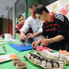 Saúl Gómez enseña a dos de los jóvenes que acudieron a la demostración a elaborar uno de los platos más típicos de la cocina japonesa, el sushi.-ISRAEL L. MURILLO