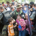 Varios refugiados ayudan ayer a uno de sus compañeros que muestra su desesperación con un niño en brazos frente a la policía de Macedonia.-Foto: AP/ D. V.
