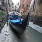 Una gondola permanece amarrada en un canal practicamente sin agua en Venecia.-ANDREA MEROLA