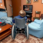 Una anciana en silla de rueda ve la televisión en su domicilio.-MONTSE ÁLVAREZ