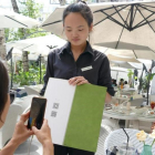 Una joven paga su consumición en un terraza de Shanghái con el teléfono móvil.-ADRIÁN FONCILLAS