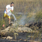 Un vecino colabora en la extinción del fuego en la barriada Yagüe.-ISRAEL L. MURILLO