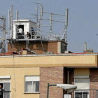 Dos técnicos revisan la instalación de las antenas de un edificio.-LOSTAU