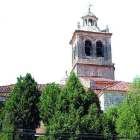 La torre de la iglesia de Santa Cruz surge entre el arbolado.-LUMIAGO