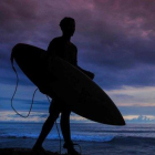 Jóvenes indonesios caminan con sus tablas de surf en una playa de Aceh, en la isla de Sumatra.-