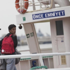 Un migrante pakistaní mira hacia atrás, conducido por un funcionario, en el ferri a punto de partir hacia Turquía, en Lesbos, este viernes.-AP / PETROS GIANNAKOURIS
