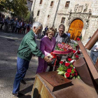 Tres asistentes depositan un ramo de flores rojas junto al monumento del Heptacordo.-SANTI OTERO