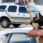 Un policía apunta con su arma a un indígena armado con un arco y flechas frente al Congreso de Brasilia.-REUTERS / GREGG NEWTON