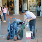 Una persona echa varias botellas de cristal en un contenedor de vidrio.-ISRAEL L. MURILLO