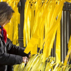 Una mujer coloca lazos amarillos en una verja-FERRAN NADEU