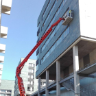 Una grúa trabaja en la fachada del hospital.-ECB